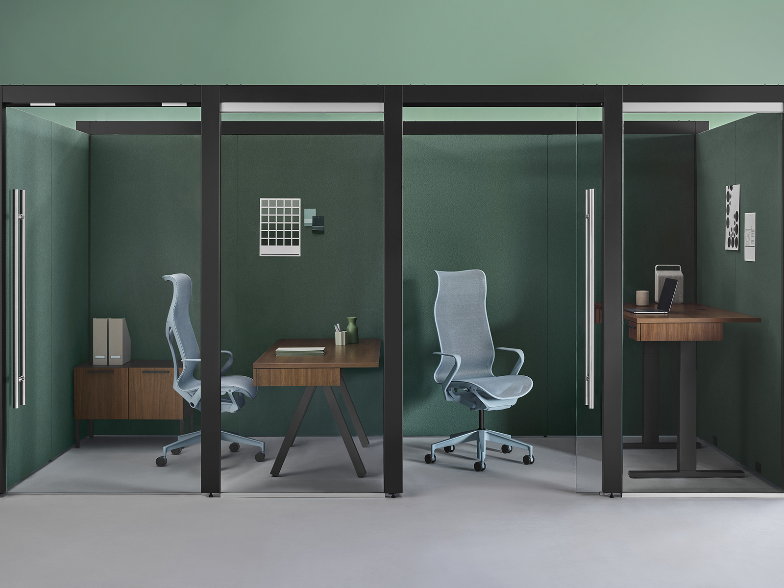 Two enclosed Overlay rooms with a walnut fixed-height desk, credenza and light blue Cosm chair in one room and a walnut Motia height-adjustable desk and light blue Cosm chair in the other.