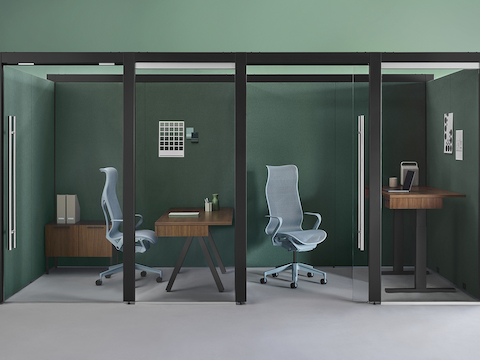 Two enclosed Overlay rooms with a walnut fixed-height desk, credenza and light blue Cosm chair in one room and a walnut Motia height-adjustable desk and light blue Cosm chair in the other.
