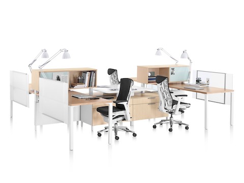 A cluster of four Canvas Office Landscape workstations with storage and surfaces in a light wood finish and black Embody office chairs.