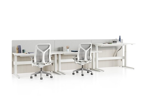 Standing desk system, Renew Link, with rectangular work surfaces, privacy screens, and Cosm Chairs. One of three desks is raised to standing height.