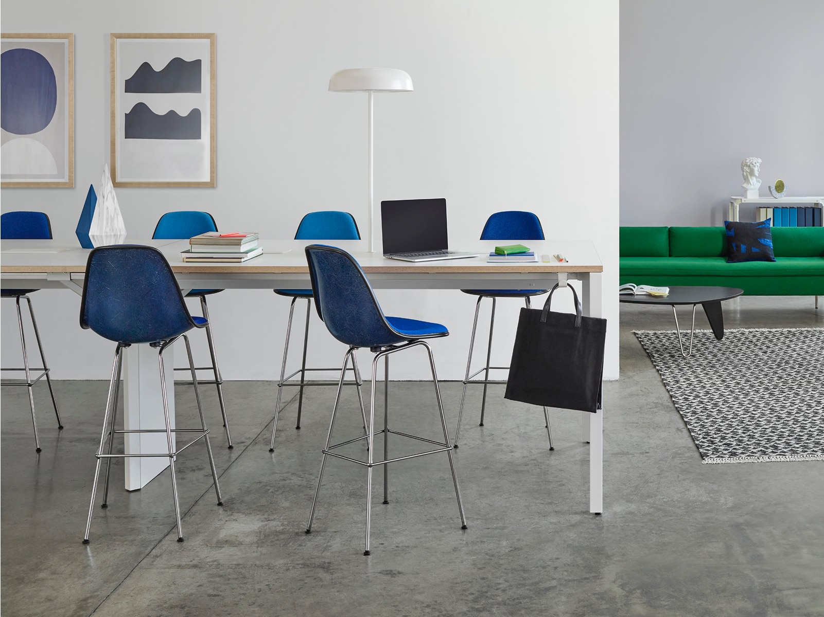 An interaction area with a Layout Studio meeting table offers a mix of seating, including a green Bolster Sofa and blue stools and side chairs.