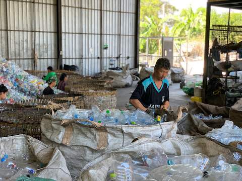 Un uomo mette in ordine delle bottiglie di plastica in un magazzino.