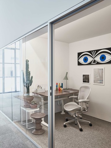 Ein privates Büro mit Glaswand im Showroom Paris, möbliert mit einem Aeron Stuhl und Atlas Schreibtisch.