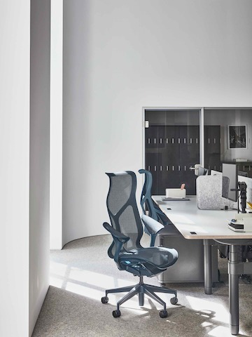 Arbeitsbereich im Showroom Paris mit blauen Cosm Stühlen mit hoher Rückenlehne um einen Atlas Schreibtisch.