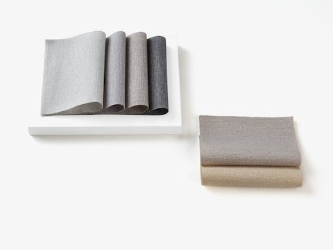 Two stacks of folded Grasscloth 100% recycled textile in neutral colors.