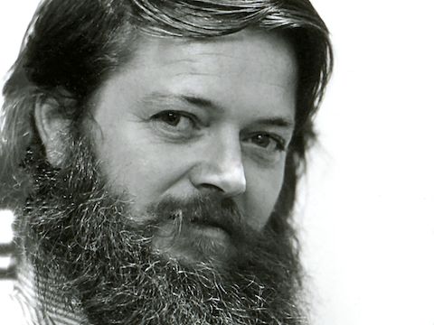 A black and white headshot of designer Ray Wilkes. Viewed at a three-quarter front angle.