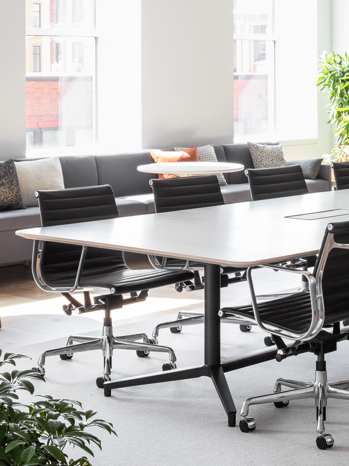 A large, well-lit conference room with a Headway Table and black Eames Aluminium Group Chairs.