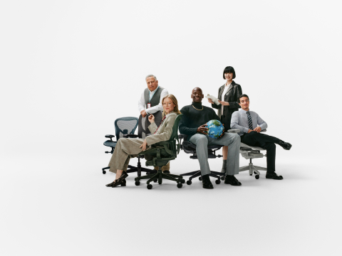 A group of five men and women in business casual clothes sitting and standing near a variety of Aeron Chairs in different colors on a white background, one holding a painted Earth ball in the center.