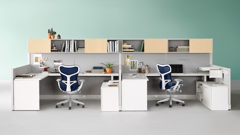 Blue Mirra 2 ergonomic desk chairs with white frames at Action Office workstations with overhead lateral storage.