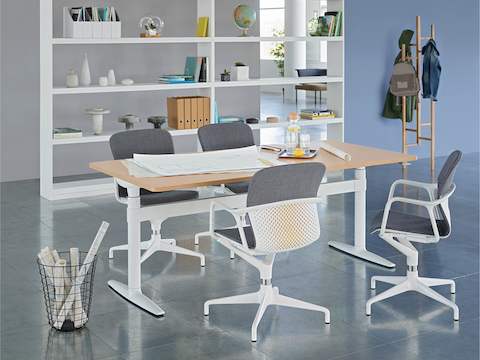 Un espace de réunion ouvert avec une table Atlas Office Landscape réglable en hauteur et quatre chaises Keyn grises.