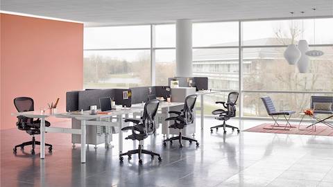 Un agencement de banc avec des chaises de bureau Aeron noires et des bureaux Atlas Office Landscape séparés par des écrans gris.