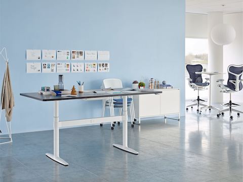 Une zone de collaboration avec une table Atlas Office Landscape réglable en hauteur, une unité de rangement et des tabourets Mirra 2 bleus.