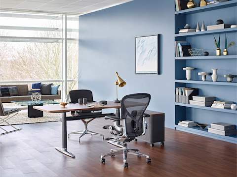Une chaise de bureau Aeron noire jumelée avec un bureau Atlas Office Landscape dans un bureau privé avec des sièges de salon et un mur de fenêtre.