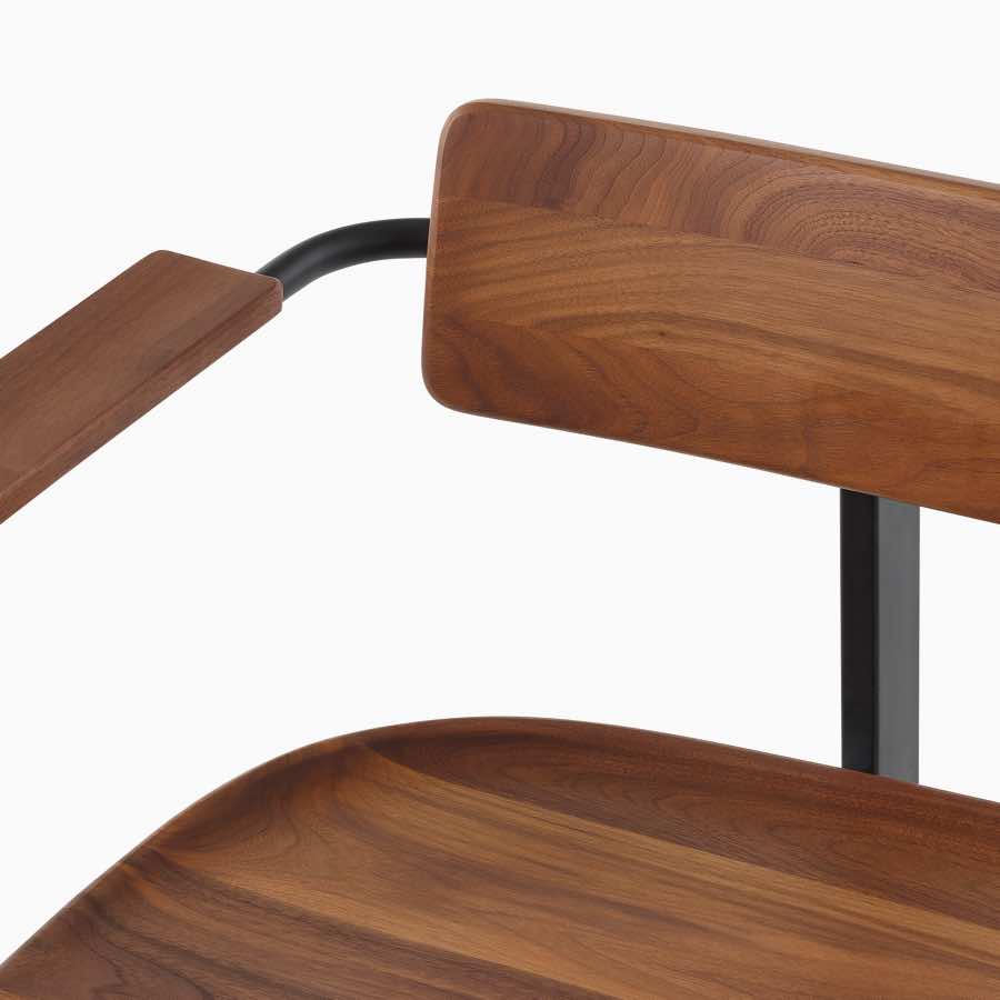 A close up of a Betwixt Bench with Walnut arms, backrest, and seat, with a black frame.