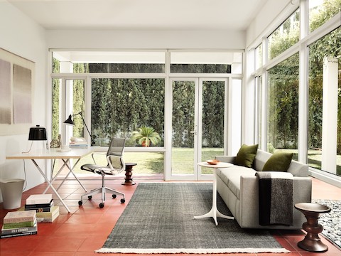 Gray Bevel Sofa with Setu Chair, Walnut Stool, Nelson X-Leg Table, and white Nelson Pedestal Table in casual setting.