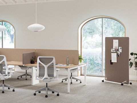 Eine helle Büroumgebung aus Layout Studio Arbeitsplätzen mit braunen Trennwänden, Cosm Stühlen sowie einer braunen mobilen Trennwand im Hintergrund.