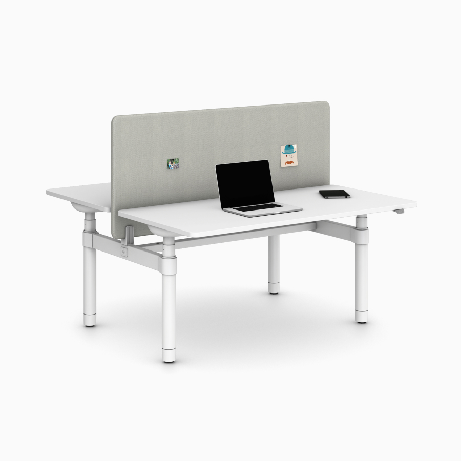 Eine hellgraue Trennwand, montiert an einem weißen Atlas Office Landscape-Arbeitsplatz mit zwei Arbeitsplatten, aus seitlichem Blickwinkel.