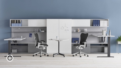 A shared Canvas Private Office with white and gray storage, one standing desk at seated height and one standing desk at standing height, and black Mirra 2 office chairs. Select to go to the Impromptu Meeting Spaces page within the Canvas Lookbook.  