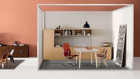 A private office using Canvas Office Landscape with an orange upholstered Eames Aluminum Group Chair and two brown Eames Shell chairs.