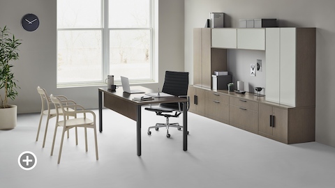 A traditional Canvas Private Office with dark wood and glass storage, a black Eames Aluminum Group office chair, and two light wood Branca side chairs. Select to go to the Private Workspaces page within the Canvas Lookbook.