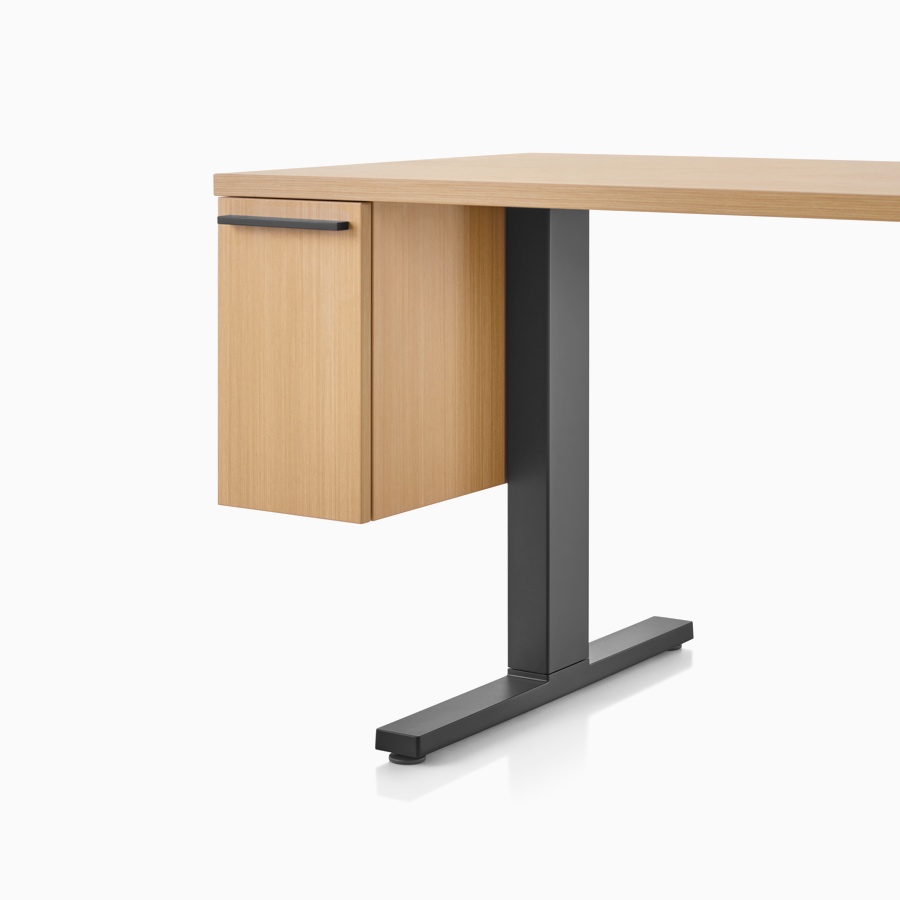 A light wood and black rectangular work surface with suspended cubby drawer and black t-shaped leg.