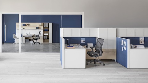 A light wood Canvas Private Office with a dark grey Cosm office chair, and a Canvas Wall workstation.
