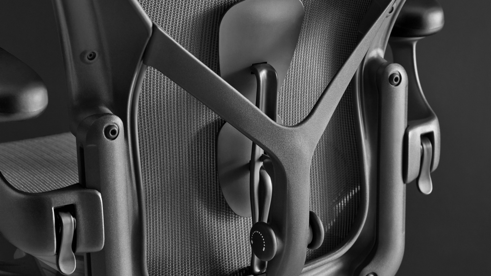 Rear view of a black Aeron ergonomic desk chair showing the PostureFit SL back support and height-adjustable arms.