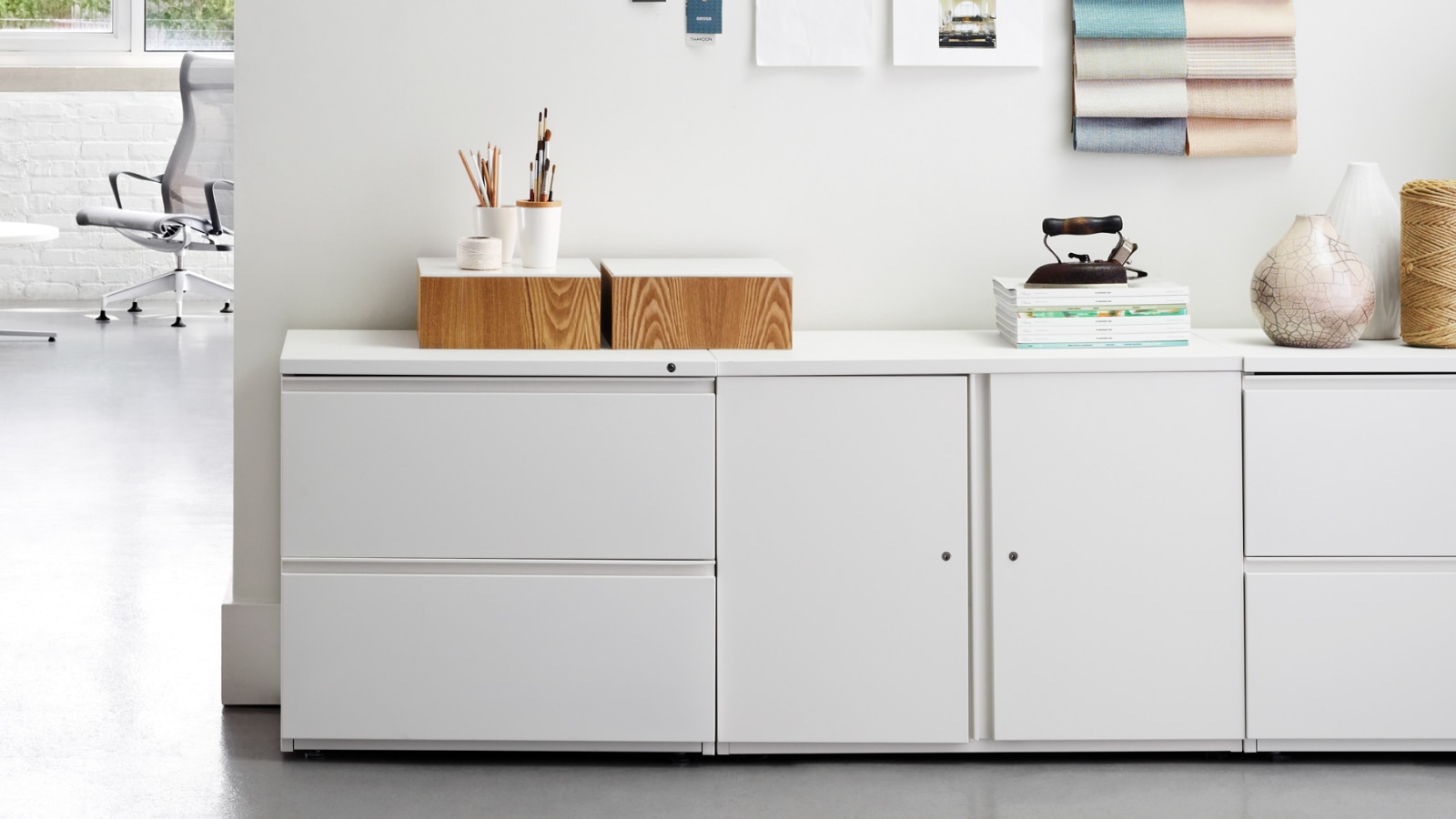 White Tu Storage cabinets and lateral files shown with accessories against a wall.