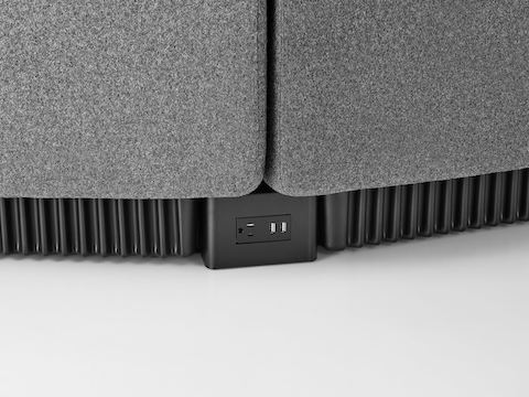 Close view of the base of connecting Chadwick Modular Seating modules, showing a receptacle with an outlet and two USB ports.