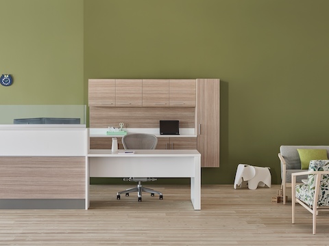 A prefab Commend Nurses Station with glass screens serving as a reception desk in an outpatient space including Palisade chairs, sofa, and table.