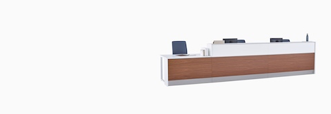A Commend Nurses Station with white Corian tops, blue Verus Chairs, walnut woodgrain laminate, and stainless steel toe kicks.