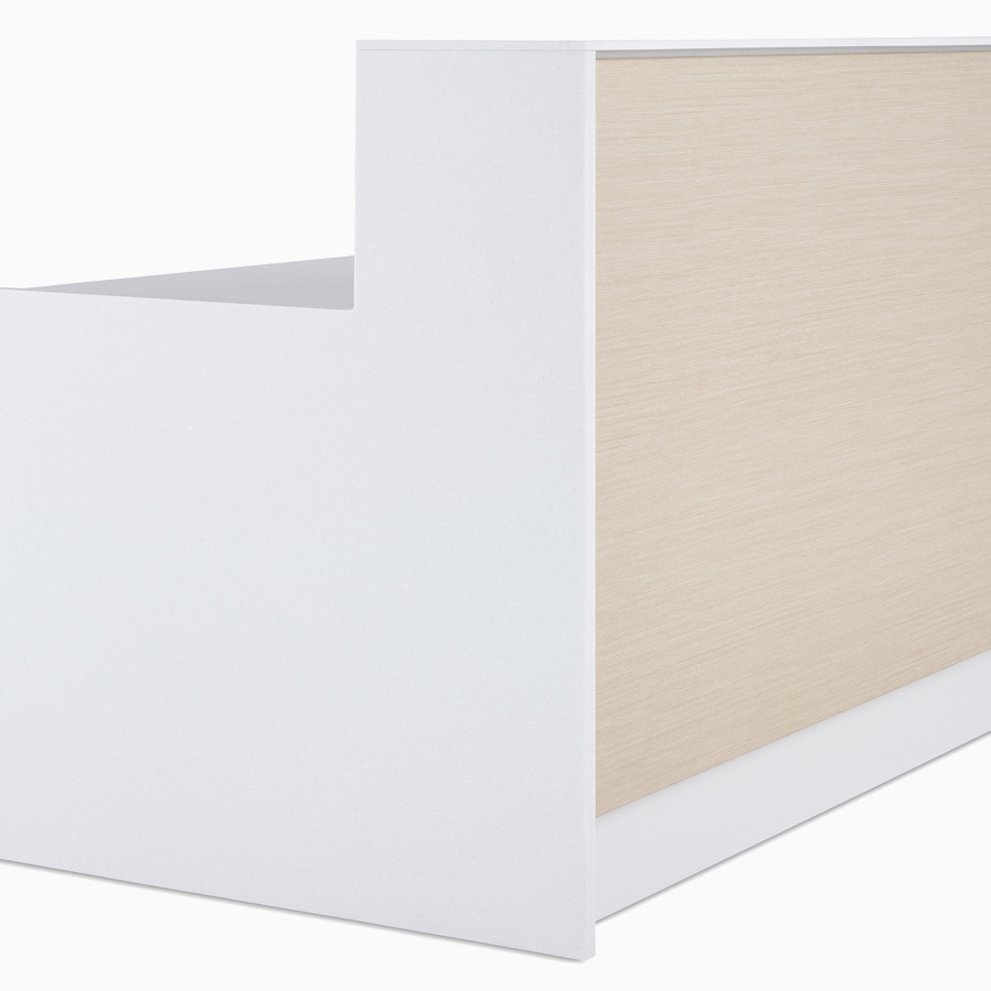 A close-up view of the one-piece exterior ash woodgrain laminate front, white Corian end panels and white laminate tops on a prefab Commend Nurses Station.