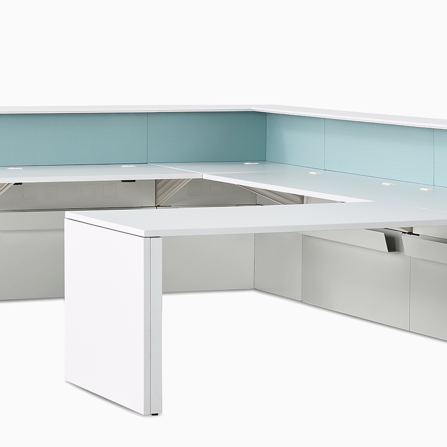 An L-shaped prefab Commend Nurses Station with mint-colored tackable fabric panels and a peninsula work surface within its interior.