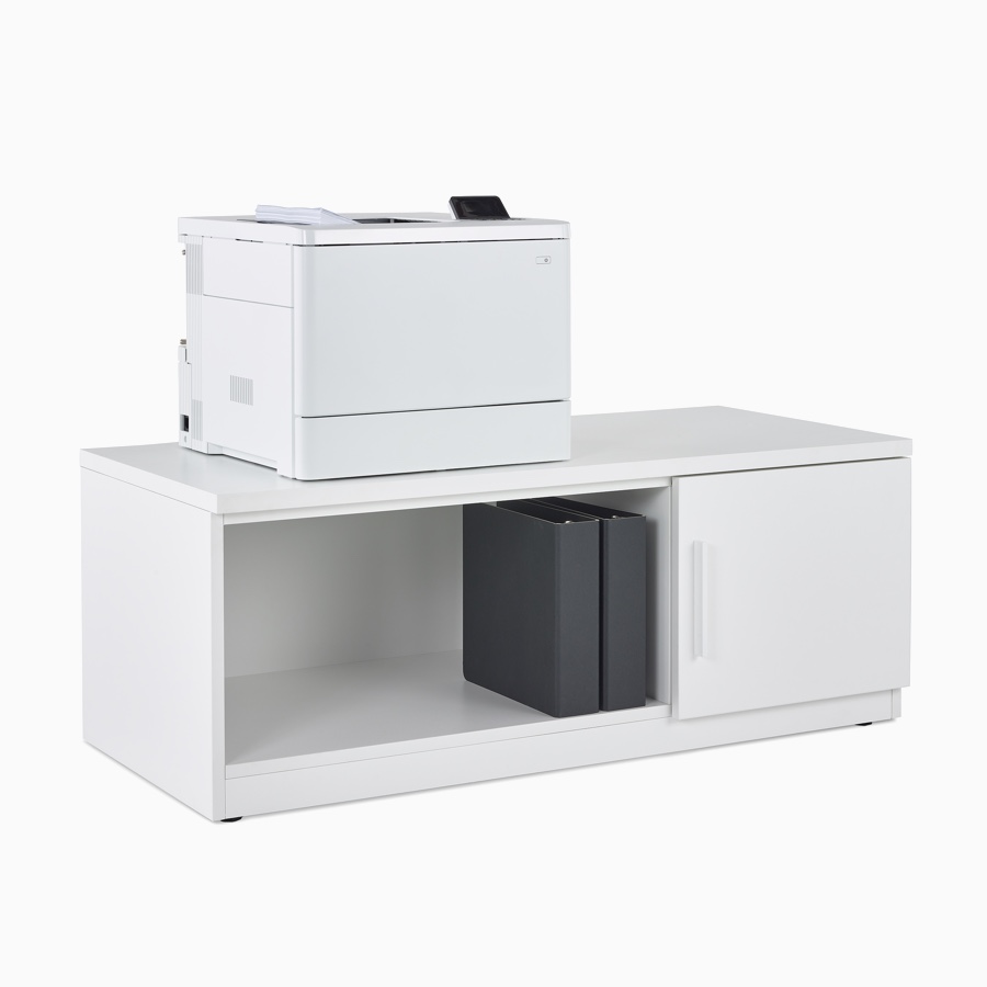 Mora System's printer storage with two cubbies, one open with two black binders and one closed, with a printer atop the storage.