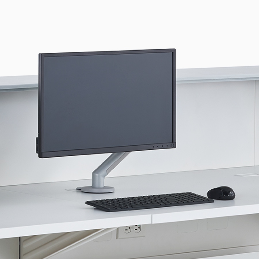 A close-up view of a Flo Monitor Arm with a screen on a prefab Commend Nurses Station white work surface.