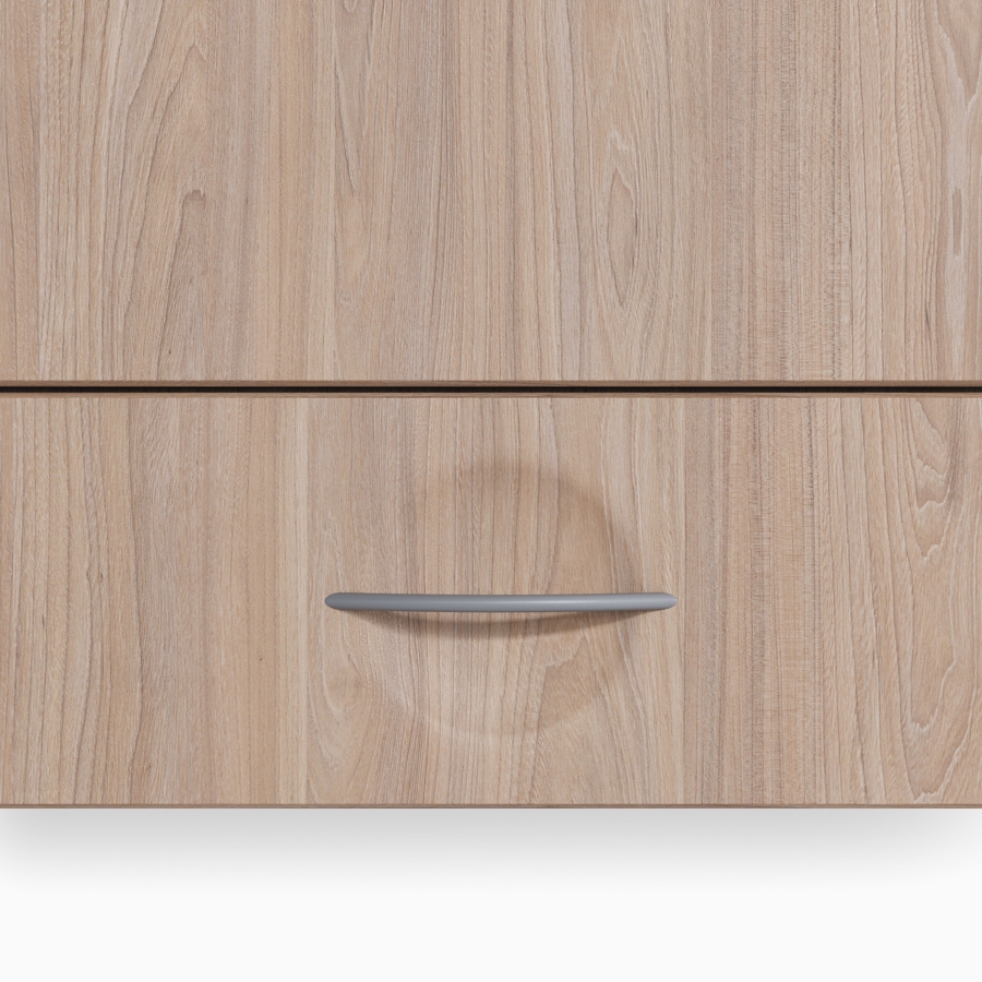 A Compass casework storage drawer in an elm wood finish and a bow pull in a gray finish.