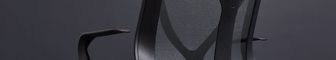 A close up of a Graphite gray Cosm Chair with fixed arms on a gray background.