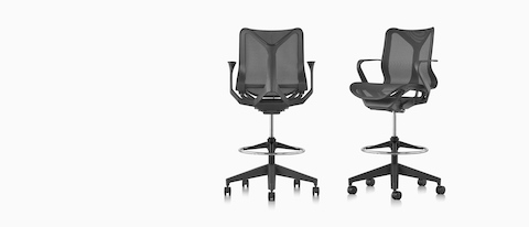Two low-back Cosm Stools in Graphite dark gray, one viewed from the back, one viewed from an angle.