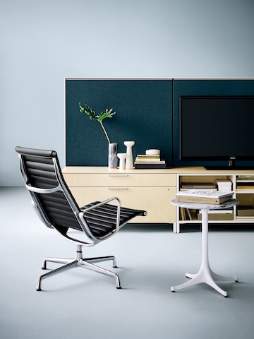 Black Eames Aluminum Group lounge chair next to a white Nelson Pedestal Table. 