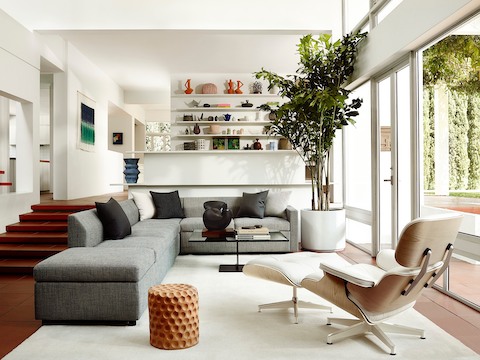 Three-quarter rear view of a white leather Eames Lounge Chair and Ottoman in a residential setting. 