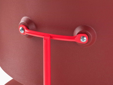 Detail view of the back of the Eames Molded Plastic Dining Chair EC-127 in all red back with plain metal screws.
