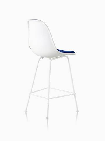 Three-quarter rear view of a white Eames Molded Plastic Stool with blue upholstery. 