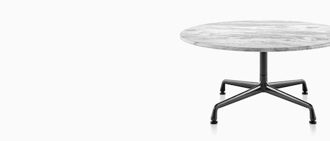 A round Eames outdoor table with a white marble top and black base.