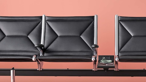 Three connected black sling seats with integrated power source on the table that includes USB-C port, USB-A port, and AC power outlet.