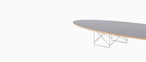 An Eames Wire Base Elliptical Table with a gray surfboard-shaped top.
