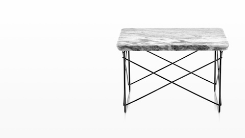 An Eames Wire Base Low Table with a stone top. 