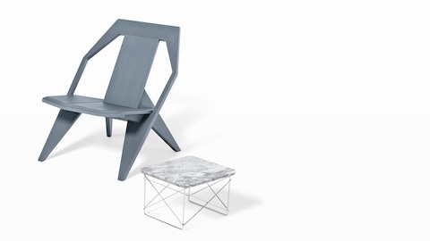 An Eames Wire Base Low outdoor table paired with a gray outdoor chair. 