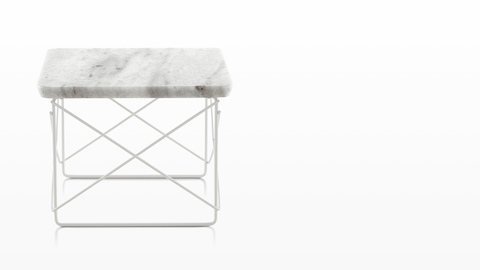 A rectangular Eames Wire Base Low outdoor table with a marble top and white wire base. 
