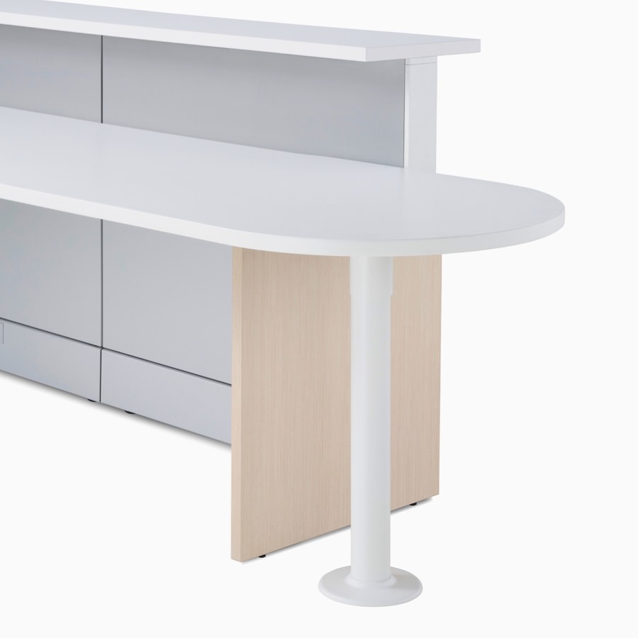 Detail of Ethospace Nurses Station in a light wood finish featuring a round-end ADA peninsula surface, white transaction top, and light gray panels.
