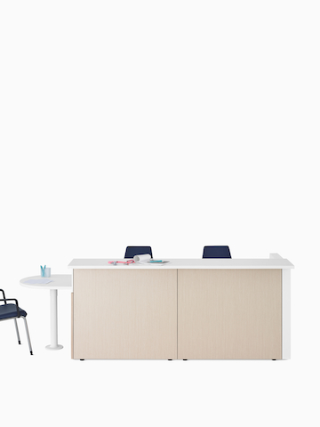 A light wood Ethospace caregivers station with transaction surface and ADA peninsula surface in white and Sayl Chairs in blue.